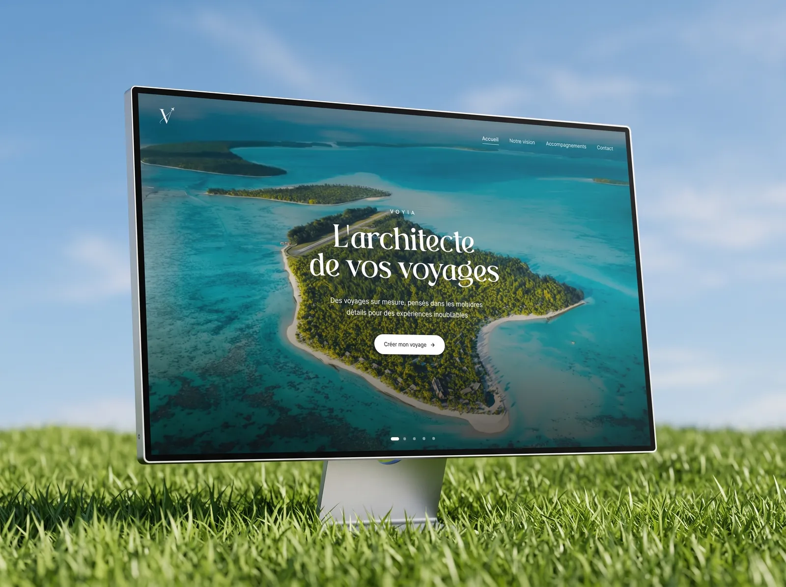Le site Voyia sur un écran posé dans l'herbe, sous un ciel bleu.